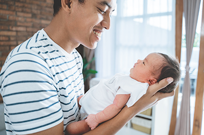 dad smiling and holding newborn on his arm